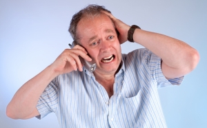 A middle aged man is upset upon receiving very bad news on the telephone.